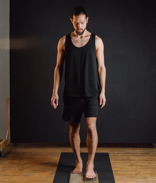 Woman in a calm yoga pose in a studio with coffee-colored background.